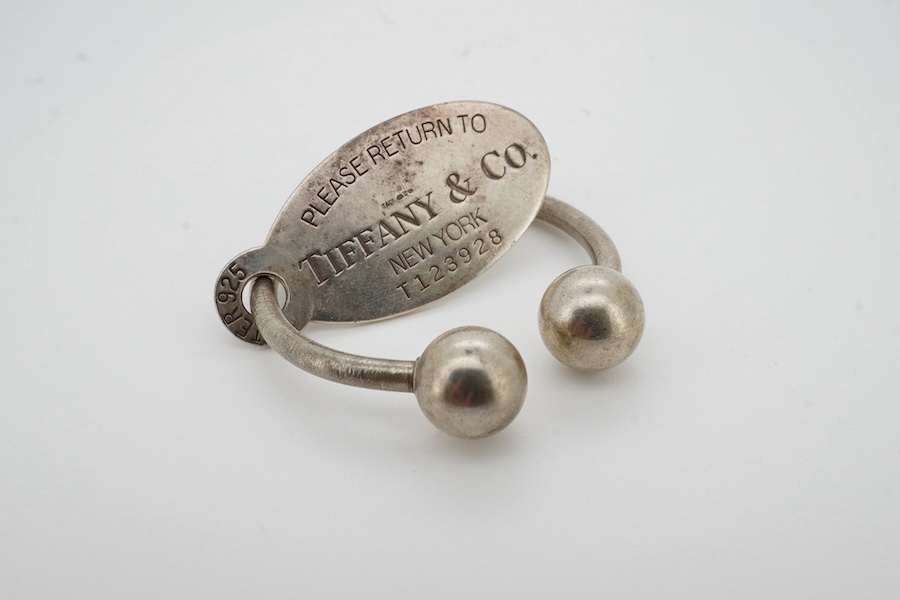Tiffany & Co, a silver scarf ring, of torque design with a hanging tag, signed Tiffany & Co., British hallmarks, sponsor's mark T&Co., length 4.5cm excluding tag, gross weight 22 grams, pouch and box stamped Tiffany & Co